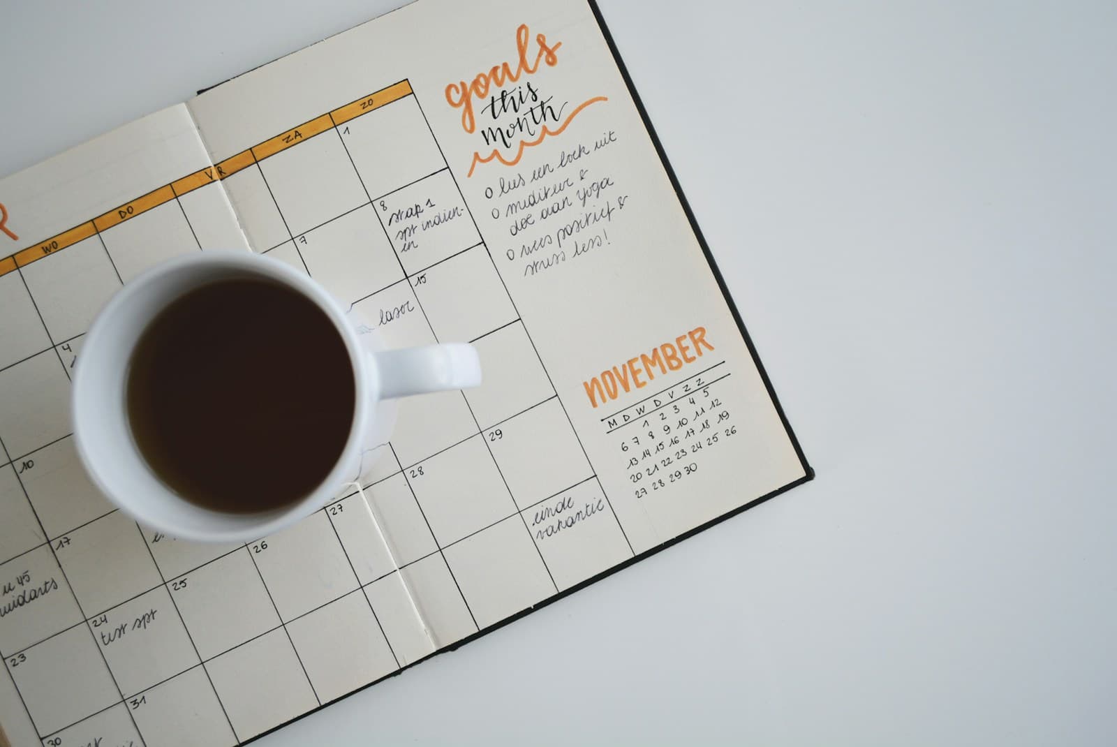 An open monthly planner beside a coffee cup, used to organize upcoming birthdays